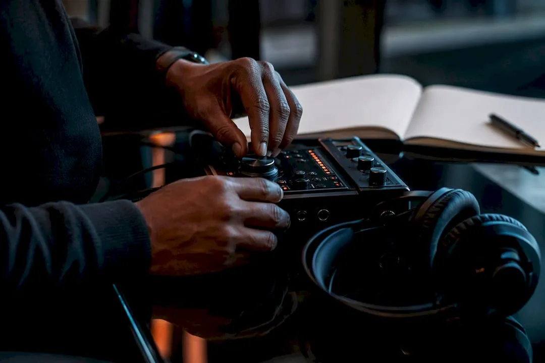 Hands adjusting audio recorder on black desk